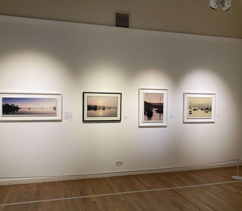 Row of framed Cornish seascape paintings at a Jamie Medlin exhibition