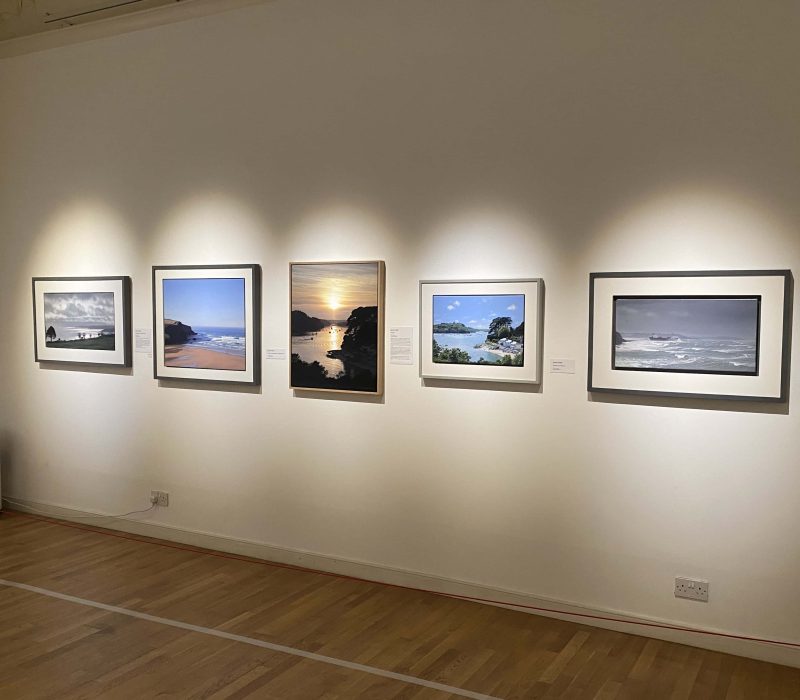 Gallery wall of framed Cornish seascape paintings at a Jamie Medlin exhibition