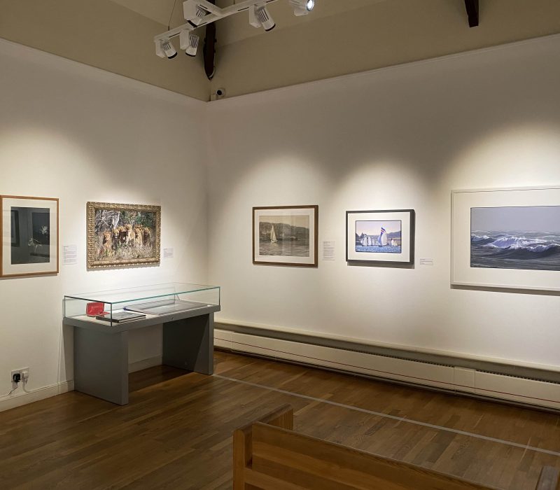 Gallery wall of framed seascapes with display plinth at a Jamie Medlin exhibition