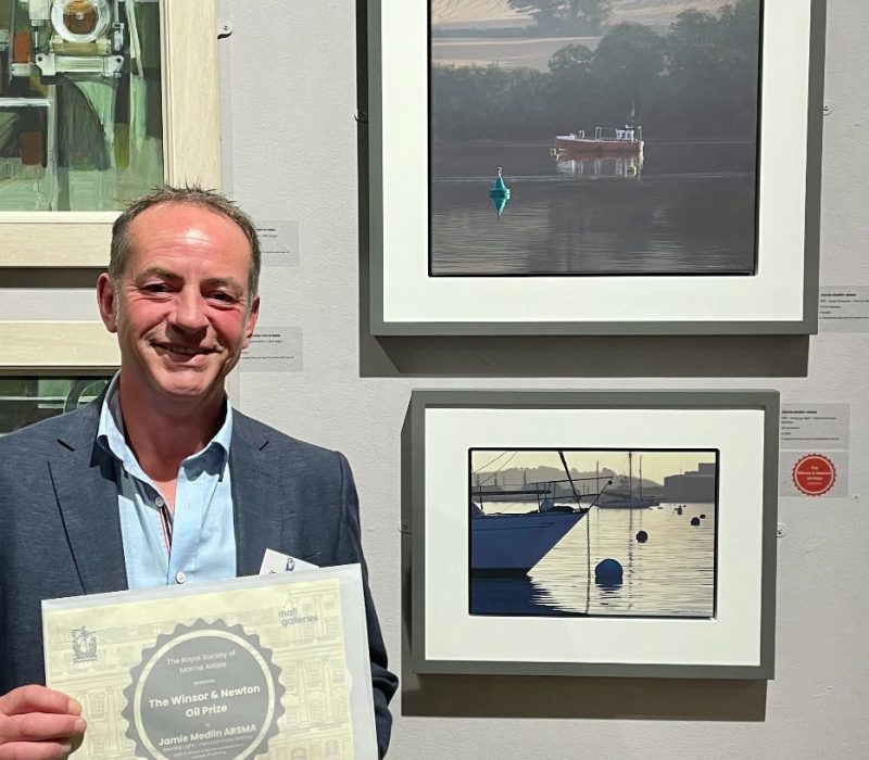 Jamie Medlin receiving a 2024 award beside his framed marine painting