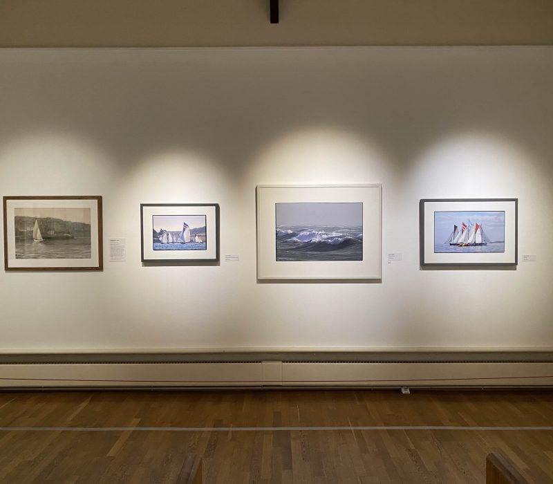 Four small framed marine paintings in a row at a Jamie Medlin show