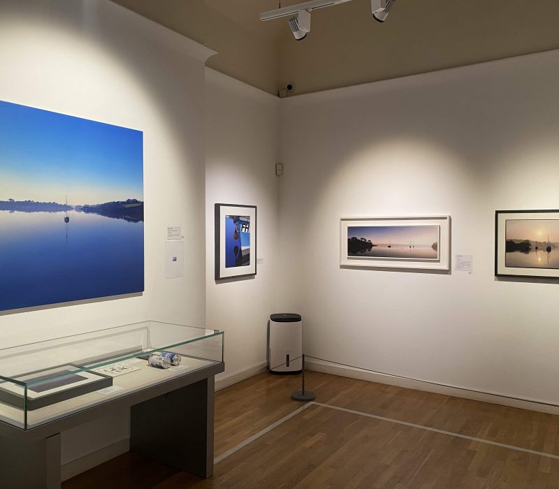 Gallery corner with framed coastal water paintings by Jamie Medlin