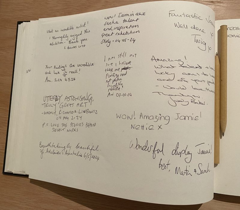 Open guestbook with visitor feedback at a Jamie Medlin art exhibition