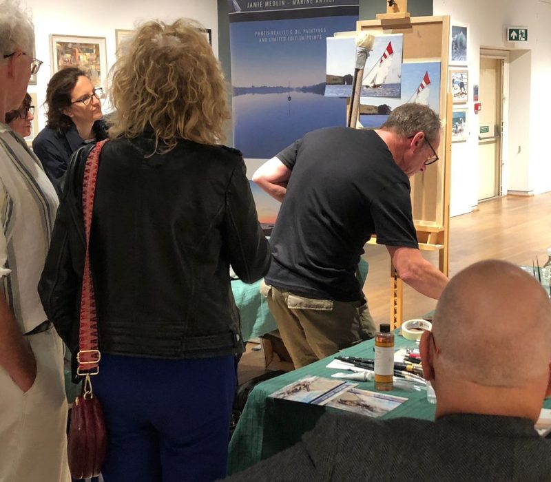 Visitors browsing artwork at a Jamie Medlin marine art event